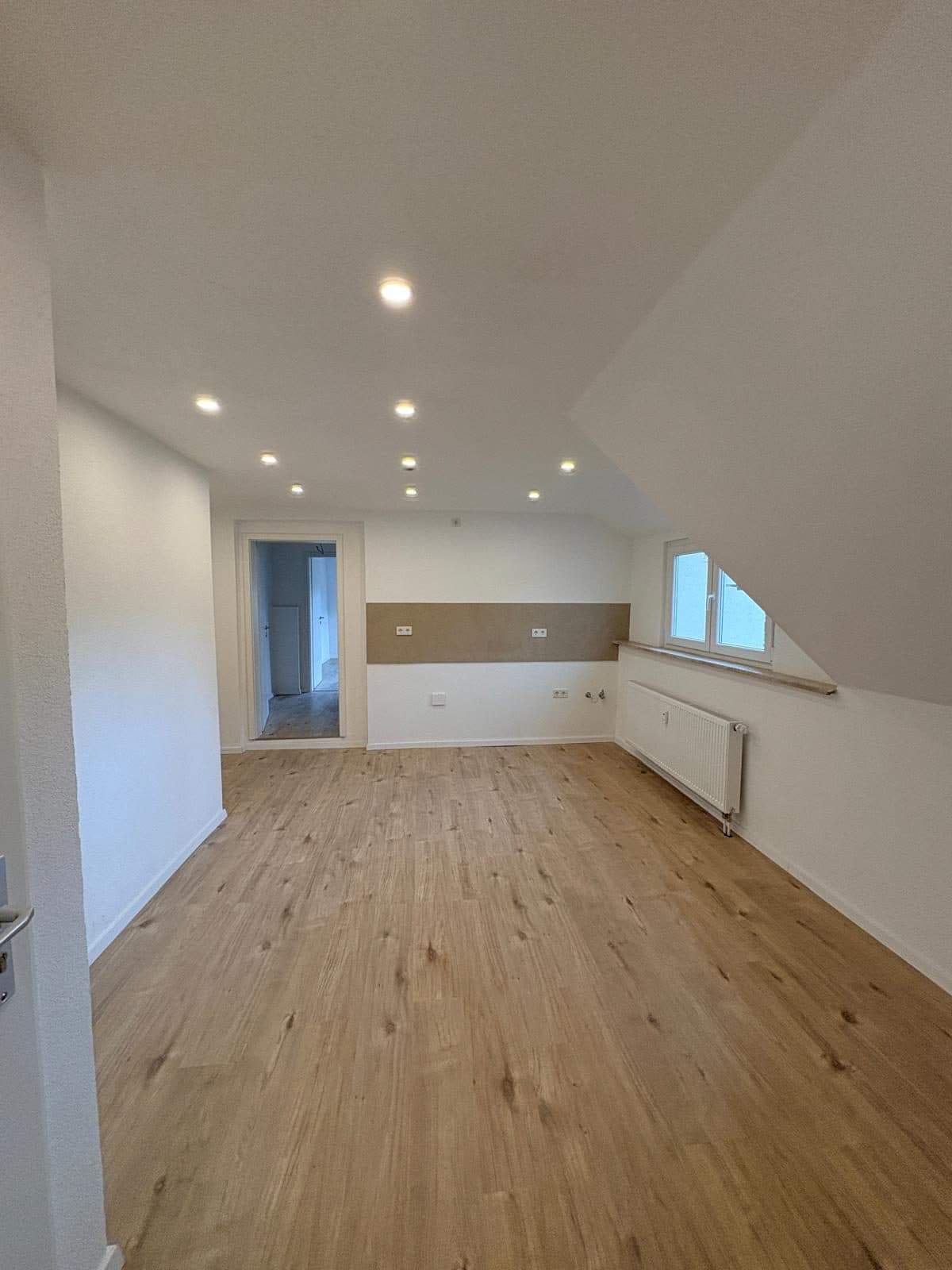 Dasselbe Dachzimmer nach der Sanierung mit Holzboden und Heizkörper