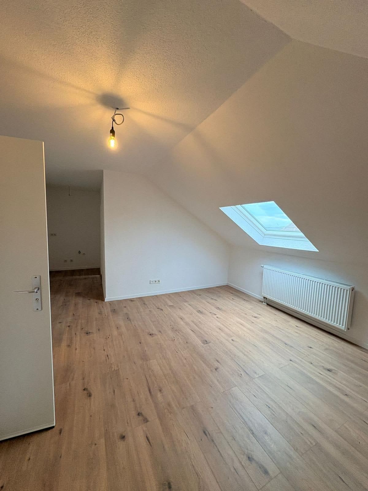 Hell saniertes Dachzimmer mit neuem Holzboden und Dachfenster