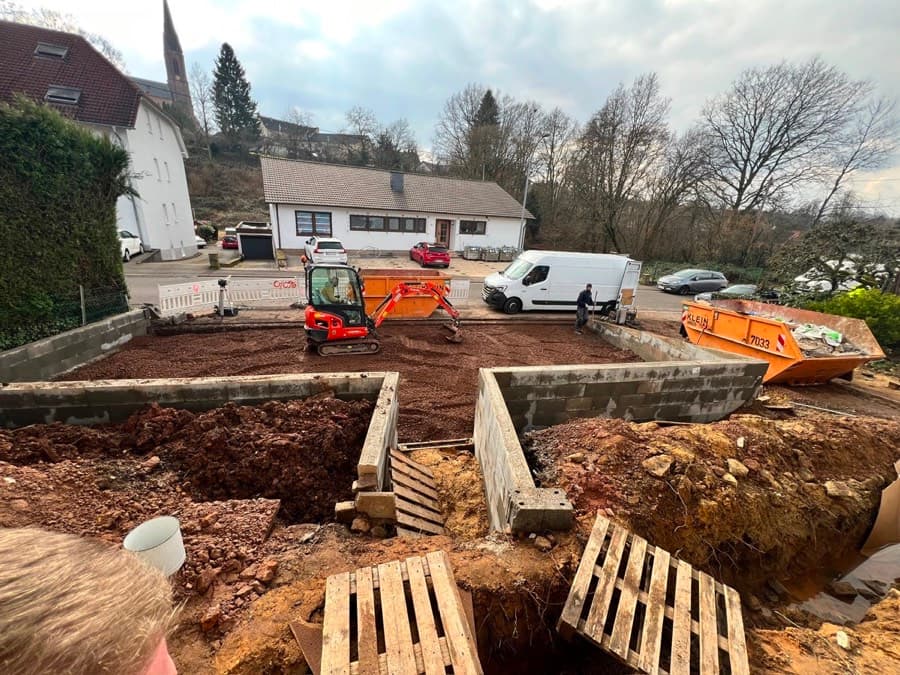 Baustelle mit Minibagger, Containern und neuen Fundamentmauern