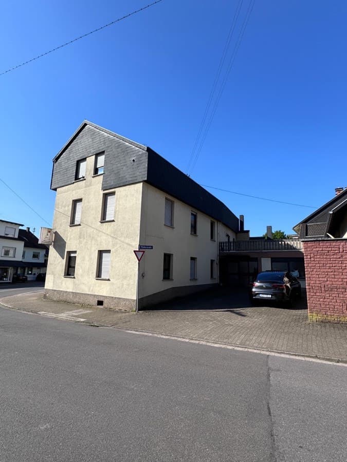 Dreigeschossiges Mehrfamilienhaus an einer Straßenecke mit überdachtem Stellplatz
