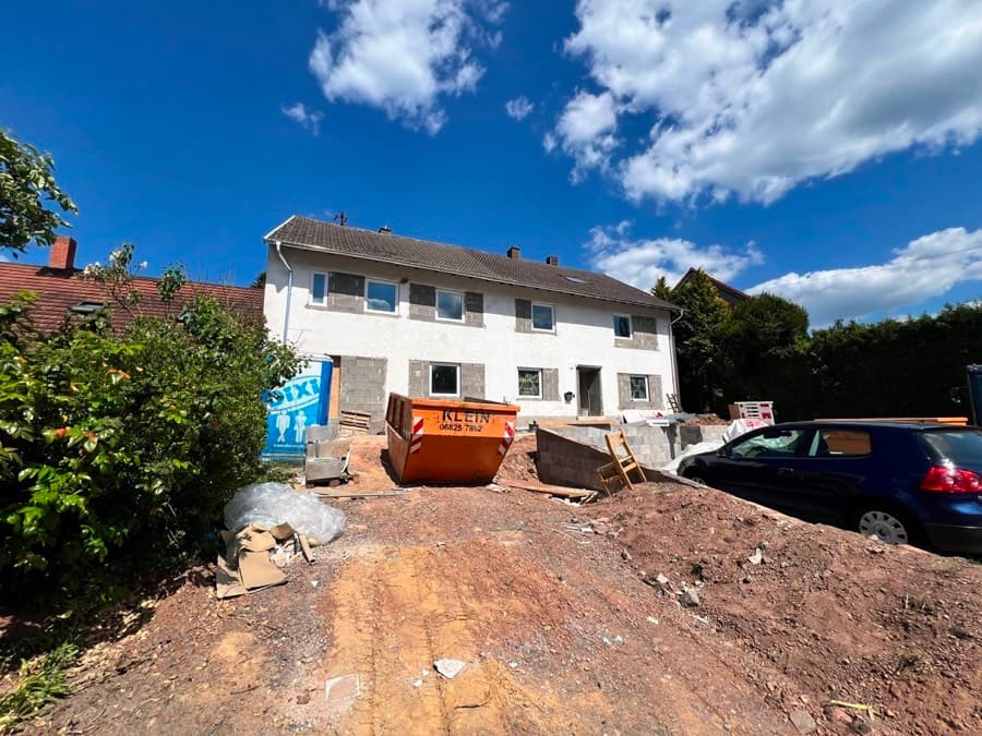 Zweigeschossiges Wohnhaus während der Sanierung mit Container und aufgegrabenem Vorplatz